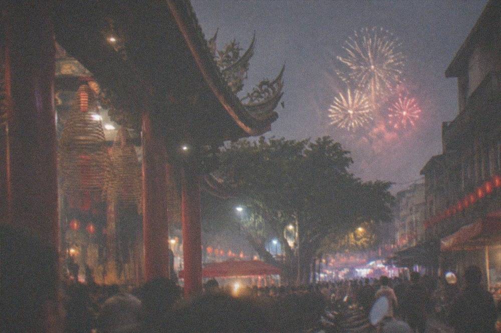 Fireworks bursting above a crowded street at night in a Taiwanese town