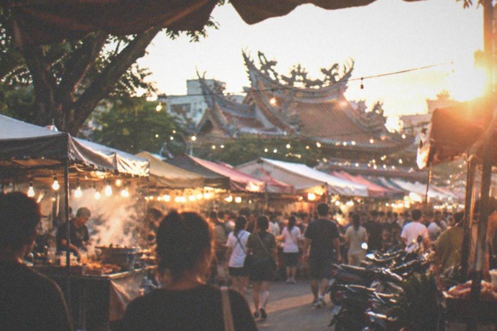 Crowded night market stalls in Tainan lit by strings of bulbs, with food steam rising over the crowd