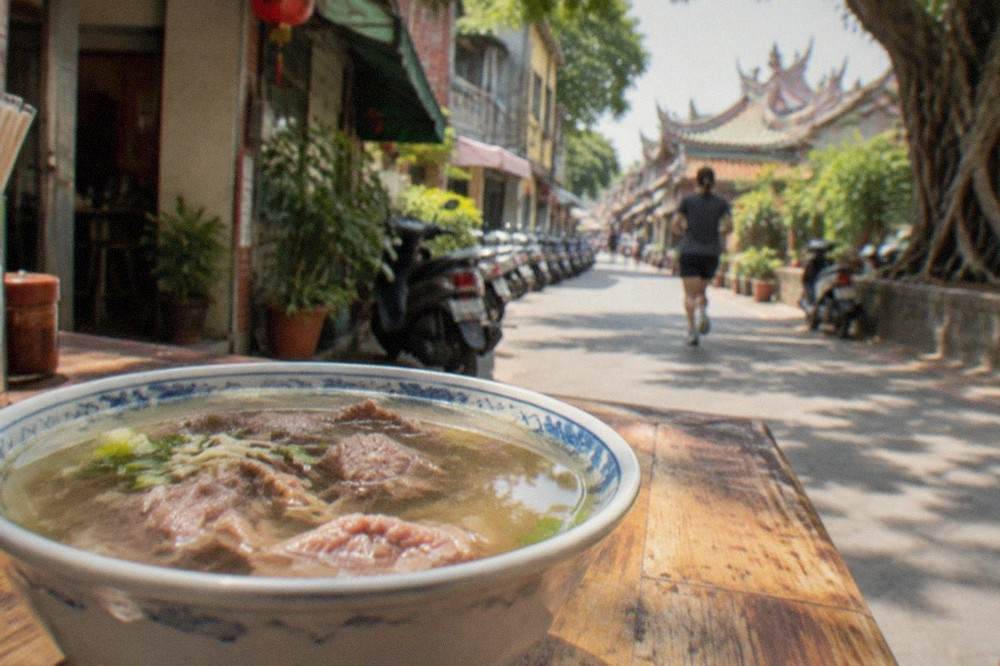 A bowl of Tainan beef soup with clear broth on a wooden table