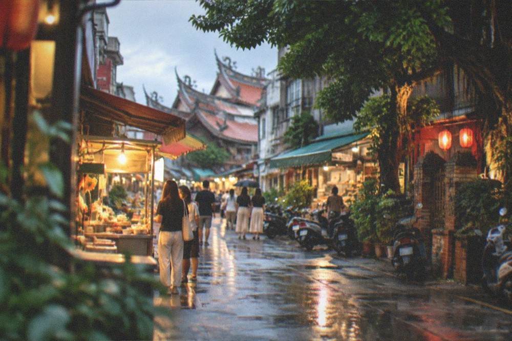 A Tainan old street in the evening with lit shopfronts and people browsing food stalls