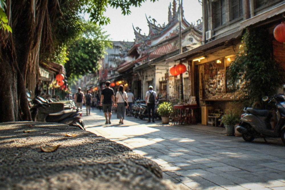 A narrow Tainan old-street lane at night with warm shop lights and people strolling