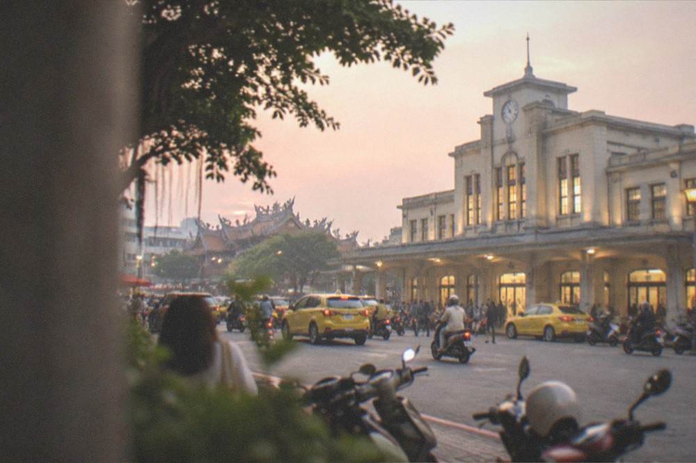 The station building at dusk with its clock and lit windows above the plaza