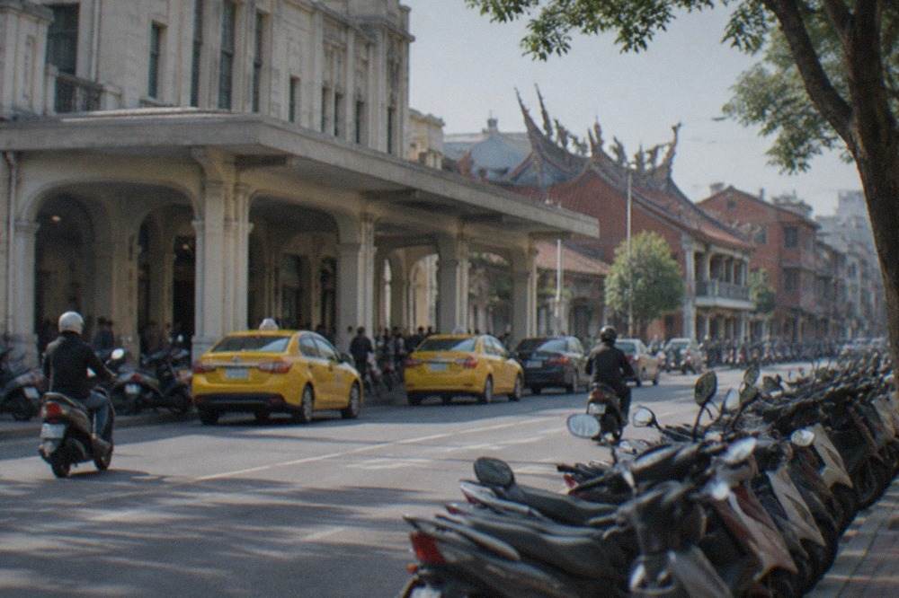 A row of parked scooters along a Tainan street with old brick buildings behind them
