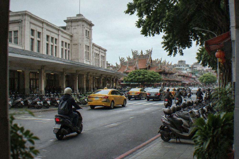 A scooter rider with a helmet on a Tainan road with temple architecture in the background