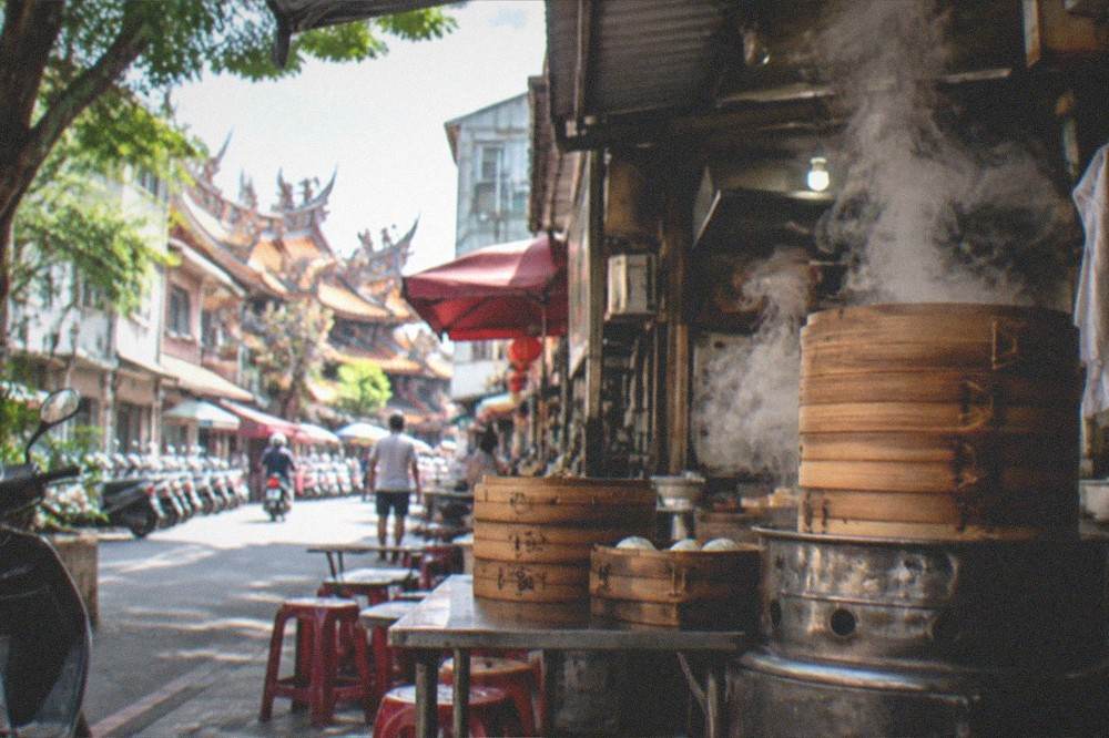 Steam rising from stacked bamboo steamer baskets at a Tainan snack shop entrance