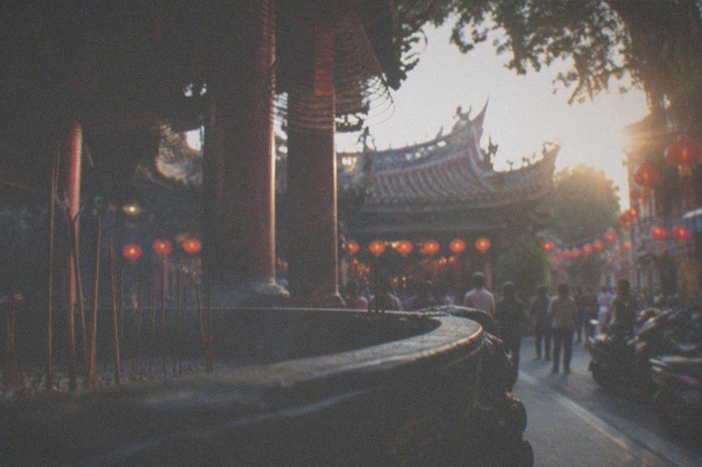 Lantern-lit temple courtyard at night during a festival with crowds in the background