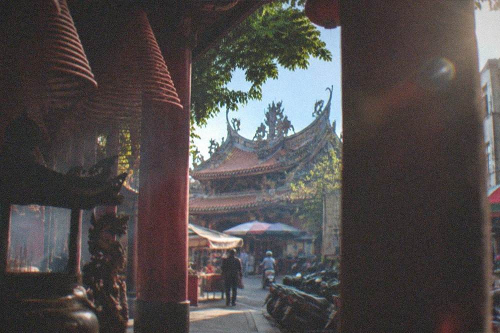 Wide view of a Tainan temple roof with curved ridges and dragon ornaments against a blue sky