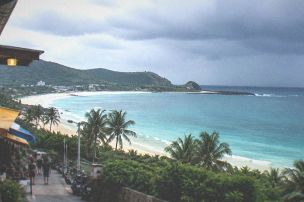 Dark storm clouds gathering over a tropical coastline with palm trees