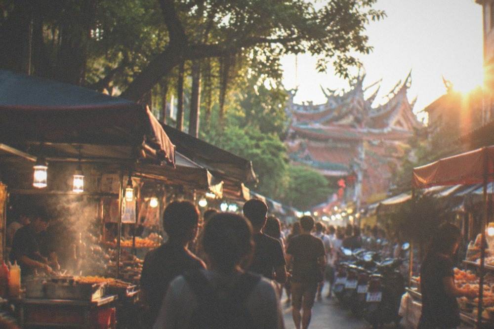 A crowded night market aisle lit by stall lights with food vendors on both sides