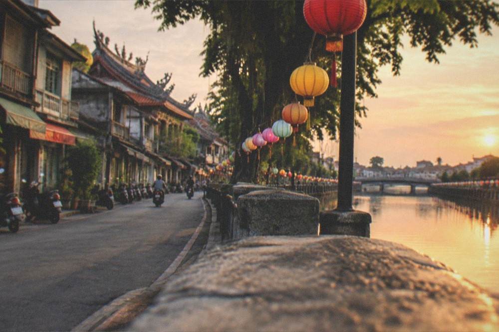Festival lanterns of different colors arranged along a waterfront promenade at dusk