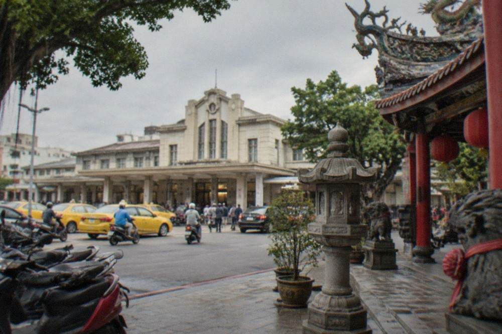 Ornate temple courtyard with red pillars, stone lanterns and carved roof decorations