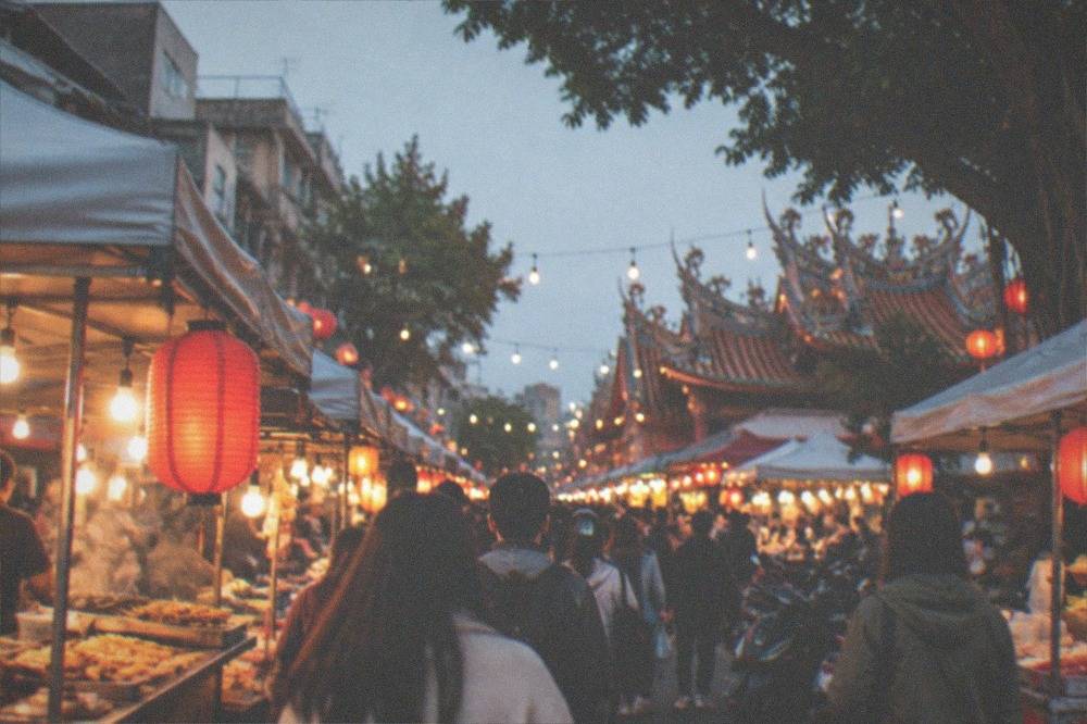 Crowded night market aisle with food stalls, red lanterns and strings of lights